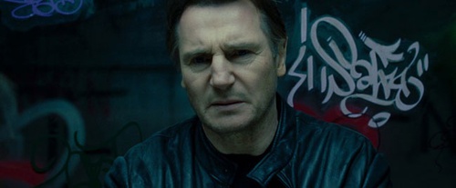 Liam neeson devant un graffiti
