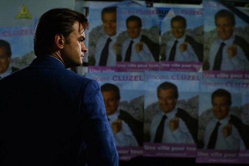 clovis cornillac devant un panneau publicitaire