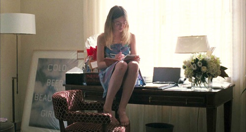 Elle Fanning assise sur le bureau